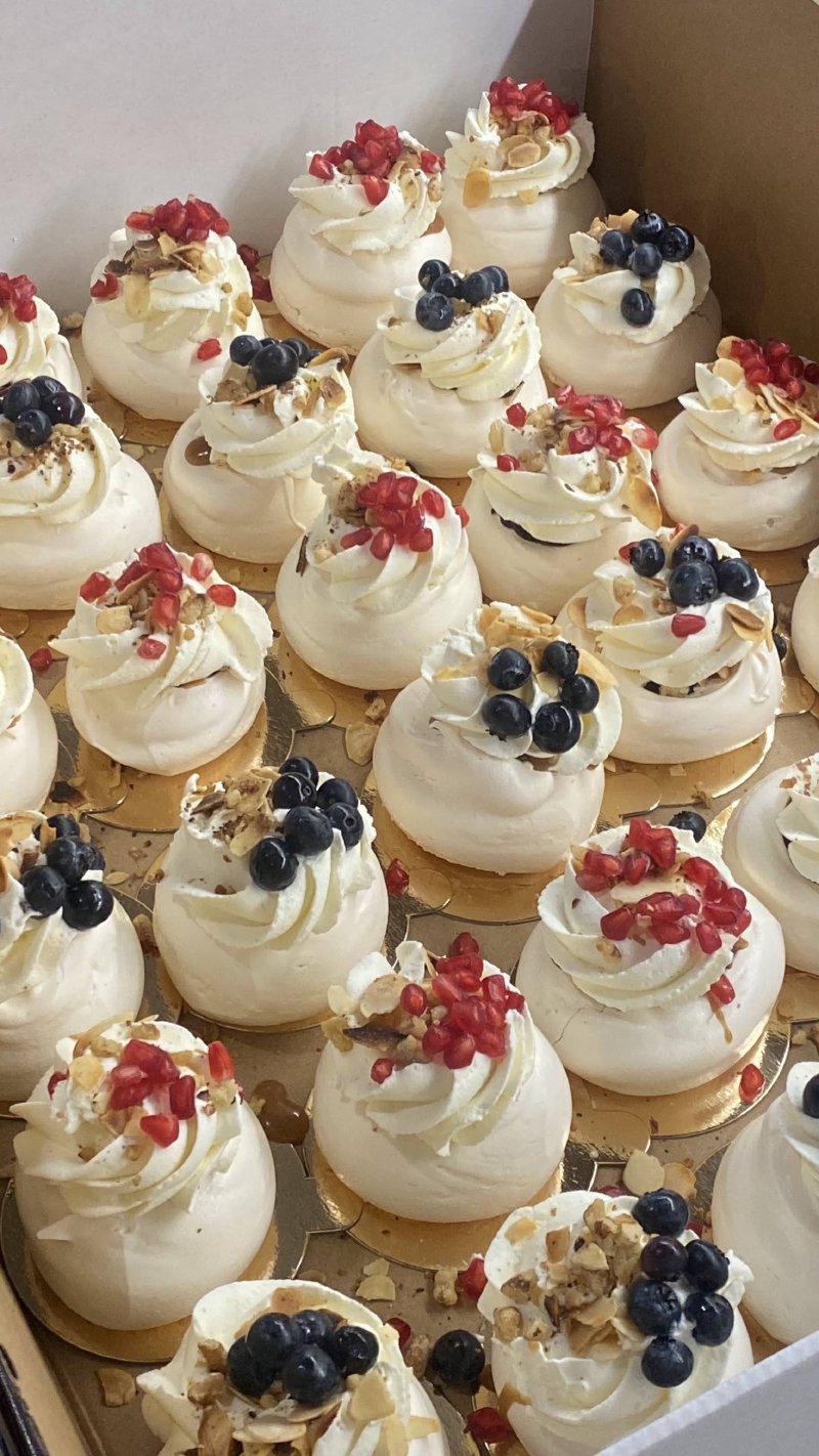 Zestaw miniaturowych bez Pavlova zdobionych owocami i orzechami.