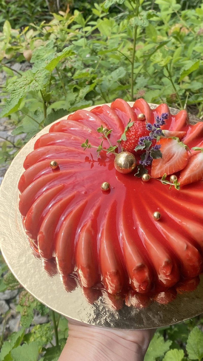 Okrągły tort musowy z czerwoną lustrzaną polewą i dekoracją ze świeżych truskawek