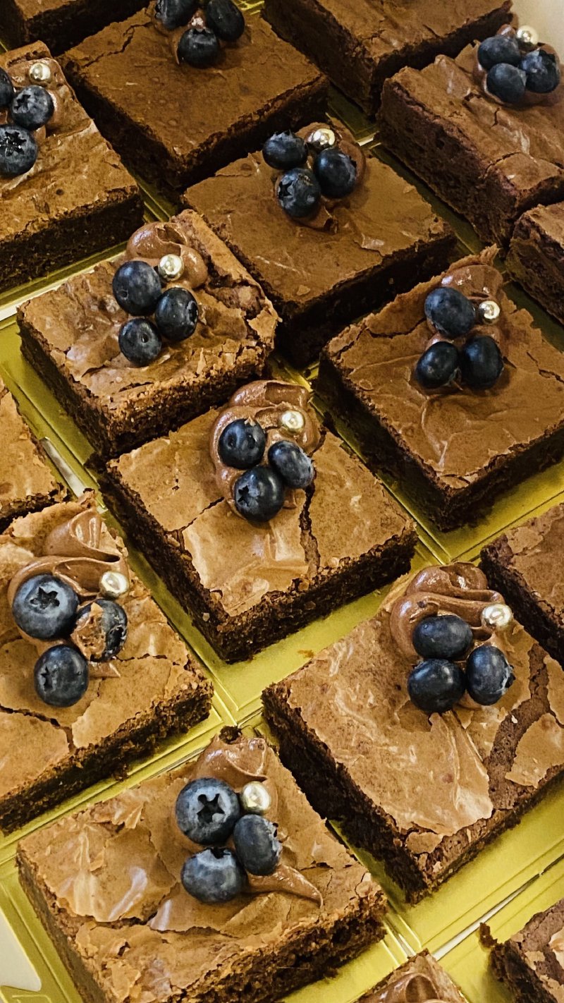 Zestaw kwadratowych, czekoladowych brownie udekorowanych borówkami.