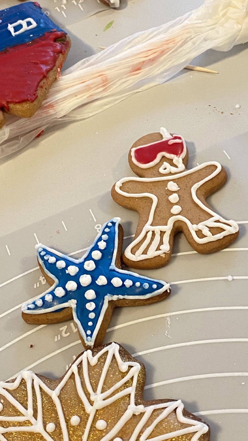 Zdobione pierniczki w kształcie ludzika narciarskiego i rozgwiazdy na macie warsztatowej.