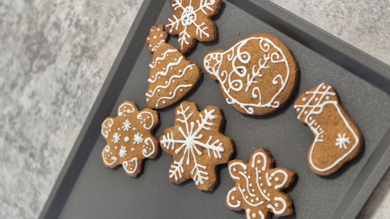 Kolekcja pierników świątecznych ozdobionych białym lukrem na szarej tacy.