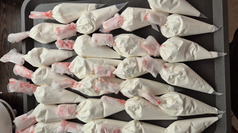 Wiele rękawów cukierniczych wypełnionych białym kremem, gotowych do użycia