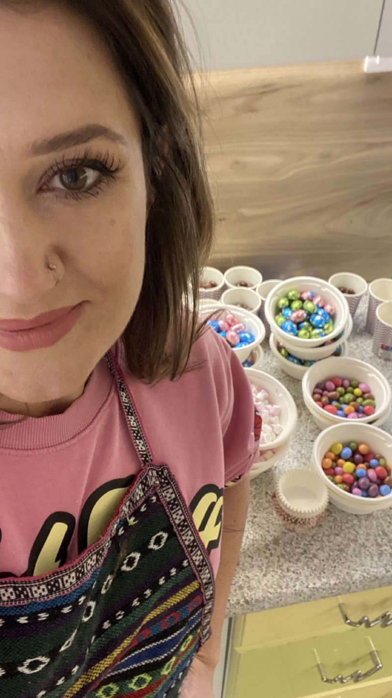 Uśmiechnięta cukierniczka w fartuchu podczas warsztatów z miseczkami dekoracji