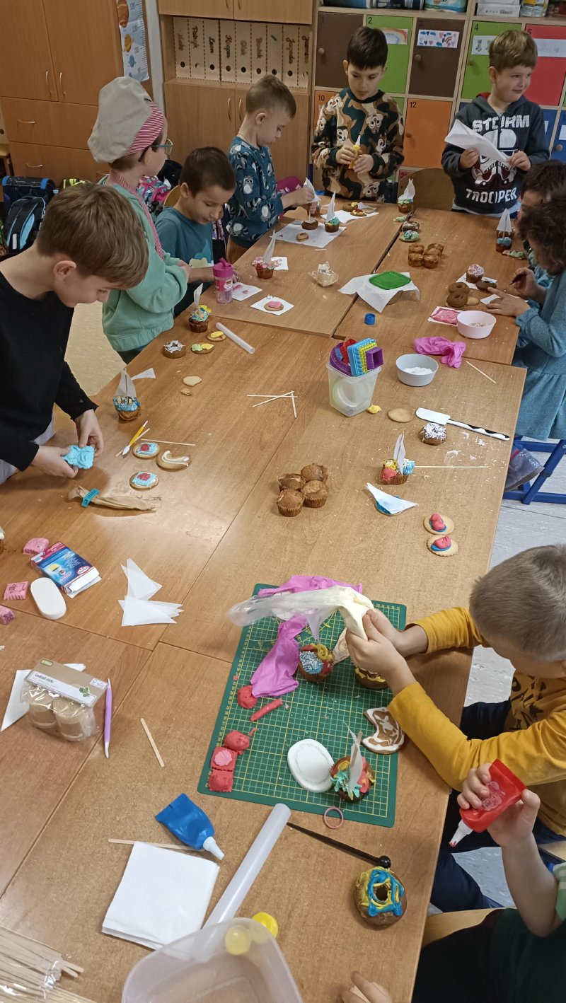 Dzieci uczestniczące aktywnie w warsztatach cukierniczych przy stole