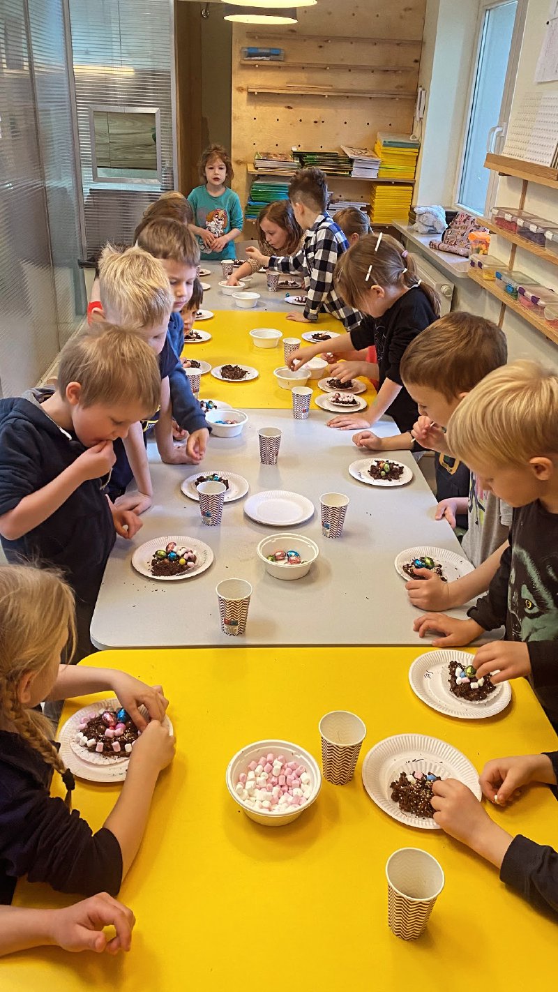 Dzieci dekorują czekoladowe wypieki kolorowymi posypkami podczas warsztatów