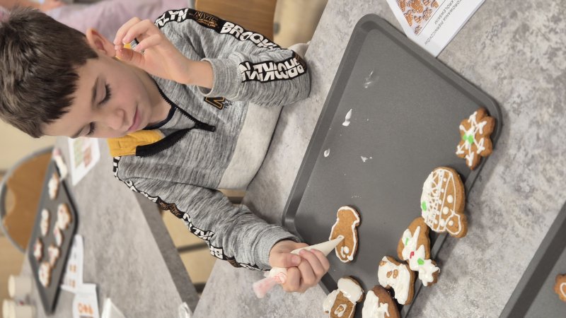 Chłopiec dekorujący pierniki lukrem podczas warsztatów cukierniczych w Zapachu Kardamonu.