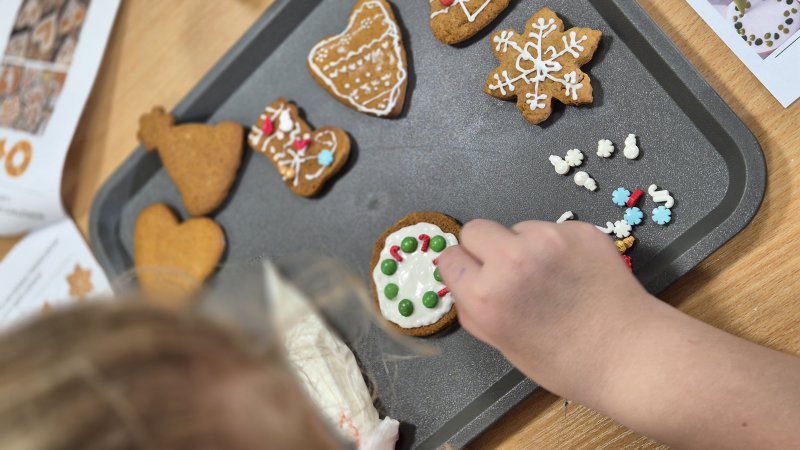 Dziecko dekoruje pierniczek lukrem na blaszce podczas warsztatów